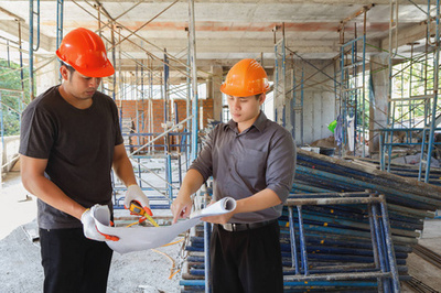 工程工具-建筑蓝图、 空白剪贴板、 分频器指南针和白色安全帽在建筑施工工地上的方格纸上